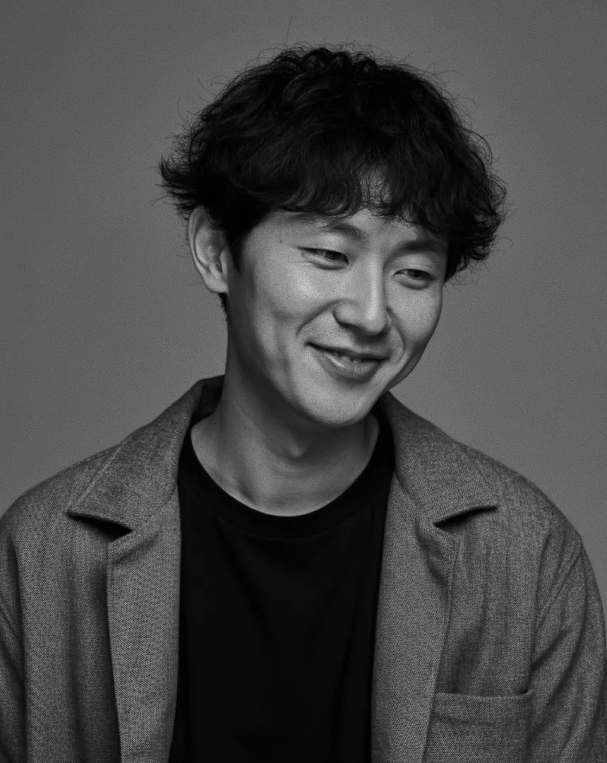 Black and white portrait of a smiling team member in casual-professional attire, symbolizing the positive impact of internal brand activation on employee engagement and company culture.
