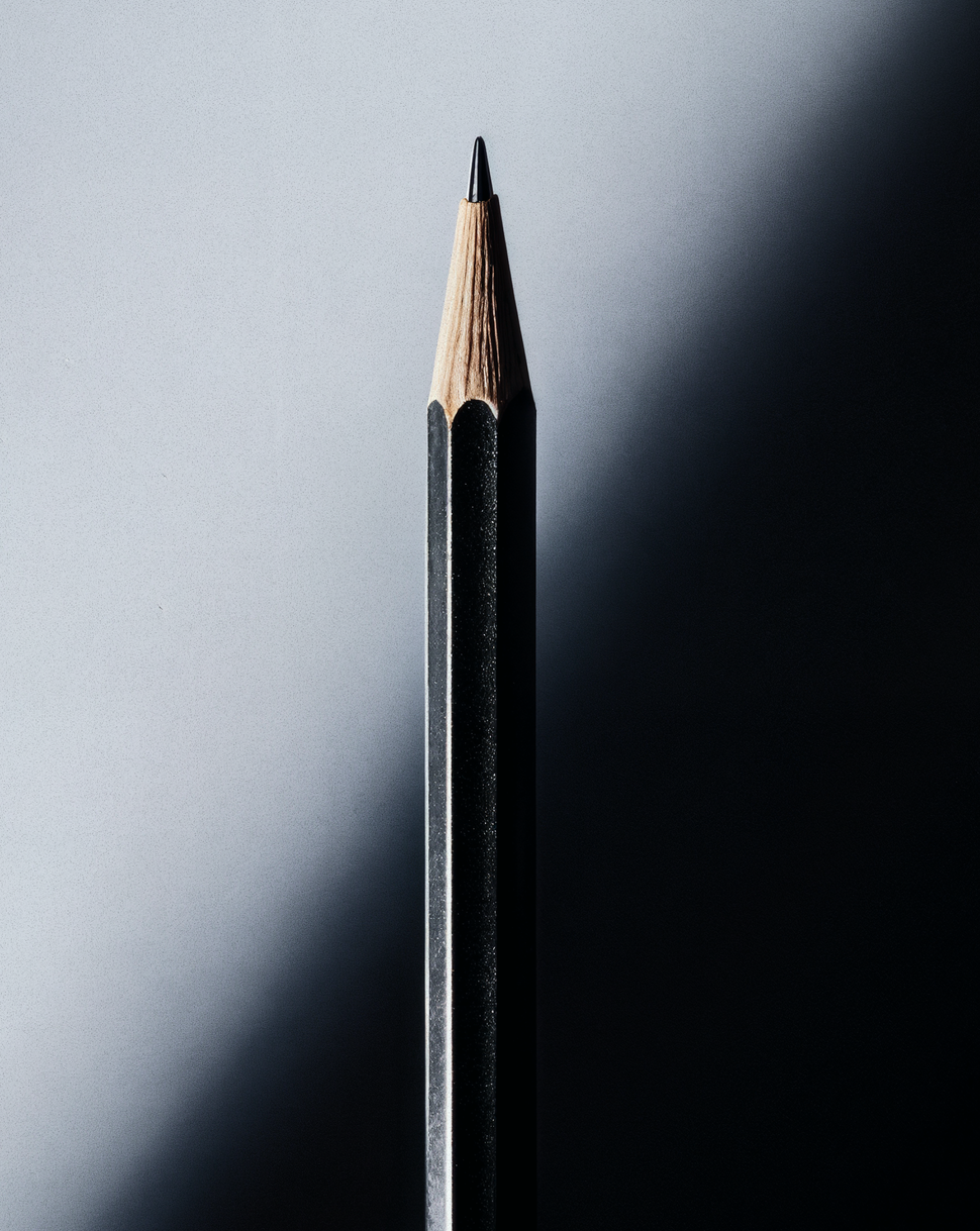 Close-up of a sharpened black pencil on a light-to-dark gradient background, symbolizing clarity and precision in refining brand messaging.